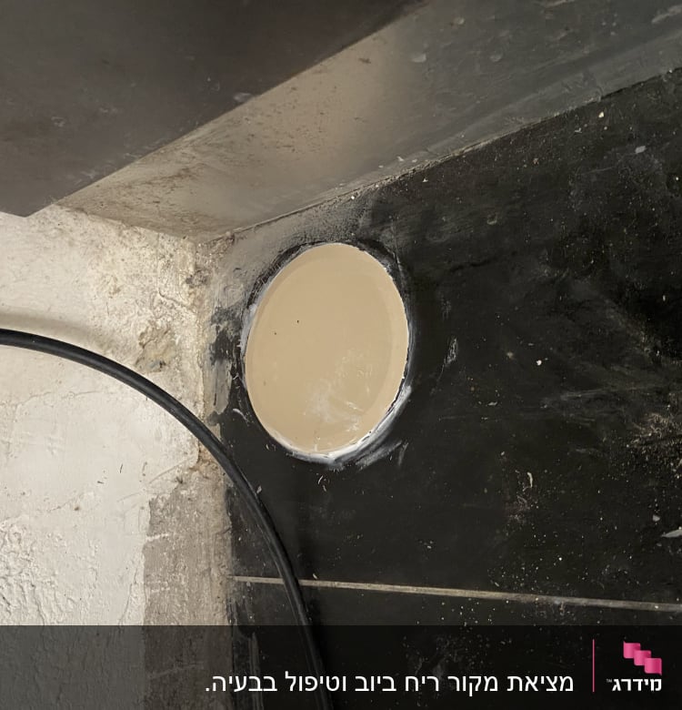צינור שחור ליד חור בקיר עם אריחים